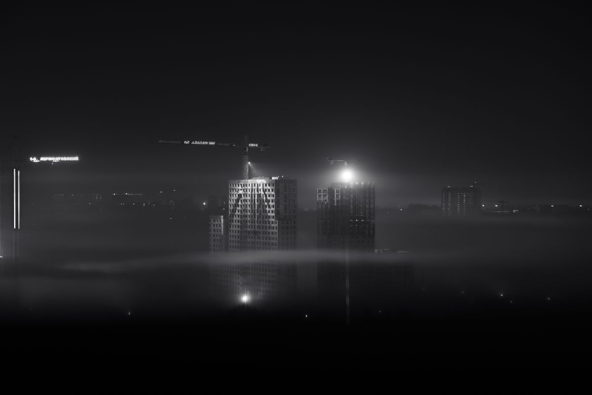 Cranes illuminated on a high-rise build at dusk