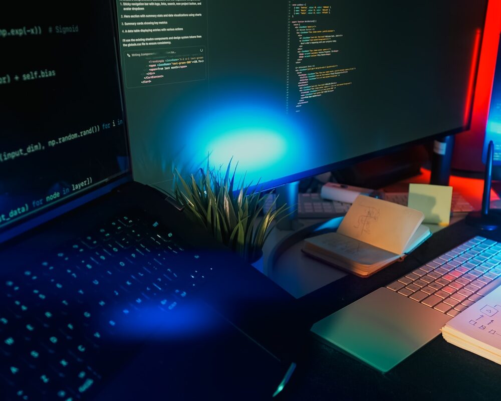 A modern developer workstation with source code on screen, lit by electric-blue light